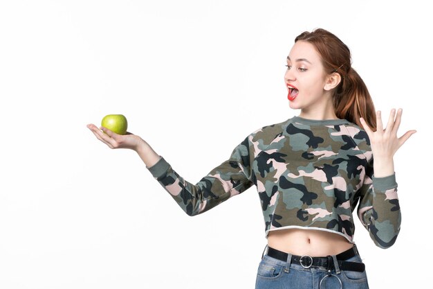 Vue de face jeune femme tenant une pomme verte blanche