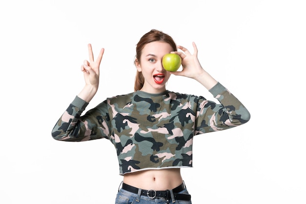 Vue de face jeune femme tenant pomme verte fond blanc régime repas couleurs plat humain nourriture arbre coup de fusil fruits