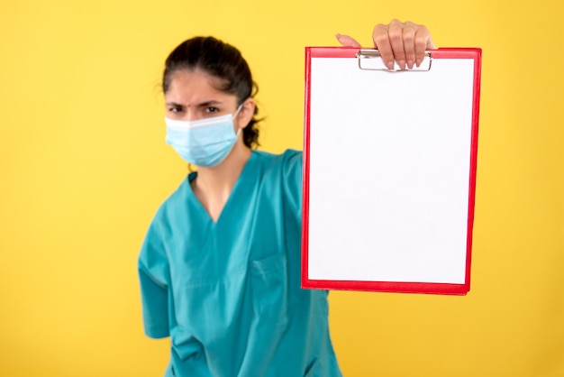 Photo gratuite vue de face de la jeune femme tenant le presse-papiers rouge sur le mur jaune