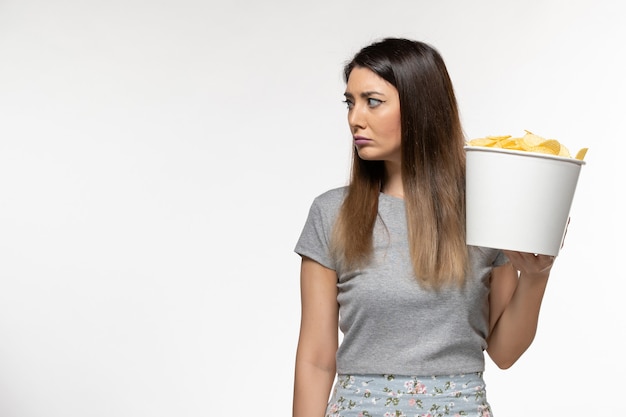 Vue de face jeune femme tenant des puces tout en regardant un film sur la surface blanche légère