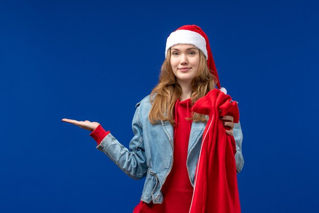 Vue de face jeune femme tenant le sac avec des cadeaux sur l'émotion de Noël de vacances de bureau bleu