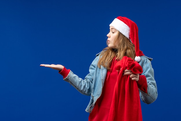 Vue de face jeune femme tenant le sac avec des cadeaux sur fond bleu vacances émotions de Noël