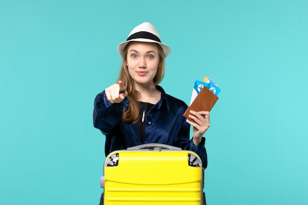 Vue de face jeune femme tenant ses billets et se préparant pour le voyage sur le fond bleu voyage voyage avion mer vacances voyage