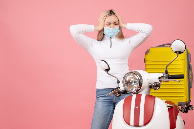 Vue de face jeune femme tenant la tête avec douleur debout près de cyclomoteur