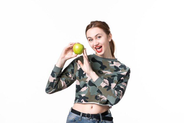 Vue de face jeune femme tenant vert pomme fond blanc repas humain jus de fruits couleurs shot régime alimentaire plat arbre pistolet