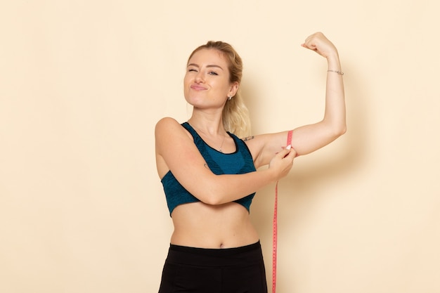 Vue de face jeune femme en tenue de sport mesurant son corps