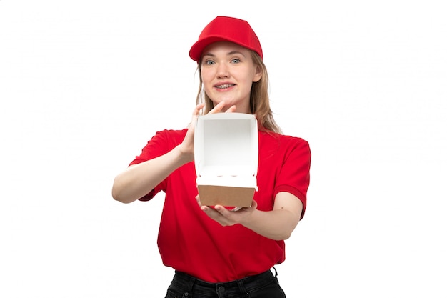 Une vue de face jeune femme travailleur de messagerie de service de livraison de nourriture souriant tenant un colis de livraison de nourriture vide sur blanc