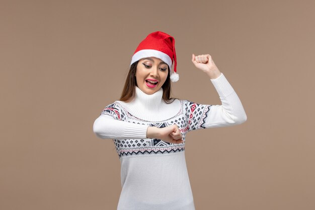 Vue de face jeune femme vérifier l'heure sur fond brun foncé émotion vacances de Noël