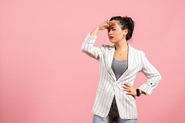 Vue de face jeune femme avec une veste blanche sur fond rose émotions femme mode femme couleur sentiment