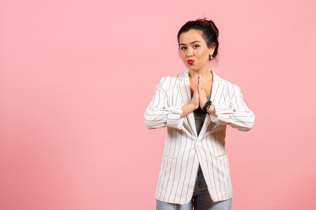 Vue de face jeune femme avec une veste blanche posant sur le fond rose mode femme émotions couleur sentiment dame