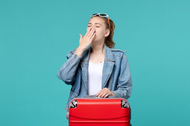 Vue de face jeune femme en veste bleue se prépare pour le voyage bâillant sur l'espace bleu