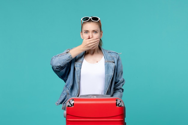 Vue de face jeune femme en veste bleue se prépare pour le voyage avec une expression surprise sur l'espace bleu