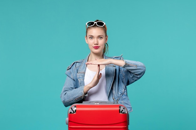 Vue de face jeune femme en veste bleue se prépare pour le voyage showign signe t sur l'espace bleu