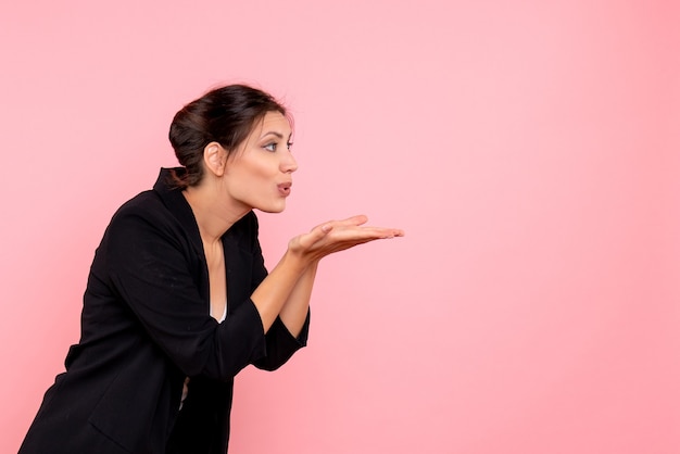 Vue de face jeune femme en veste sombre sur un bureau rose