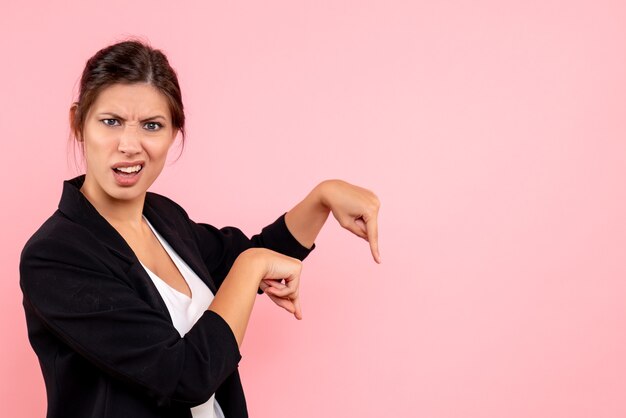 Vue de face jeune femme en veste sombre sur un bureau rose