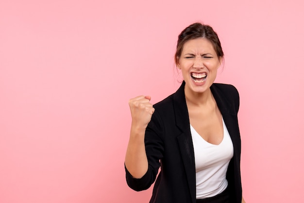 Vue de face jeune femme en veste sombre se réjouissant sur fond rose