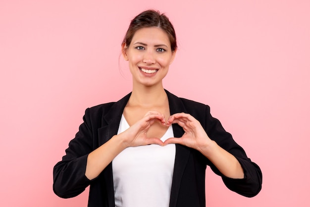 Vue de face jeune femme en veste sombre souriant et envoyant de l'amour sur fond rose