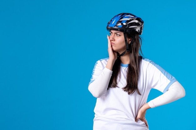 Vue de face jeune femme en vêtements de sport avec casque sur mur bleu