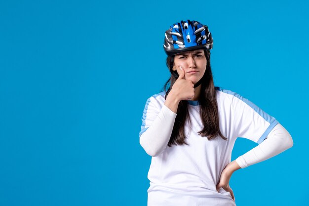 Vue de face jeune femme en vêtements de sport avec casque sur mur bleu