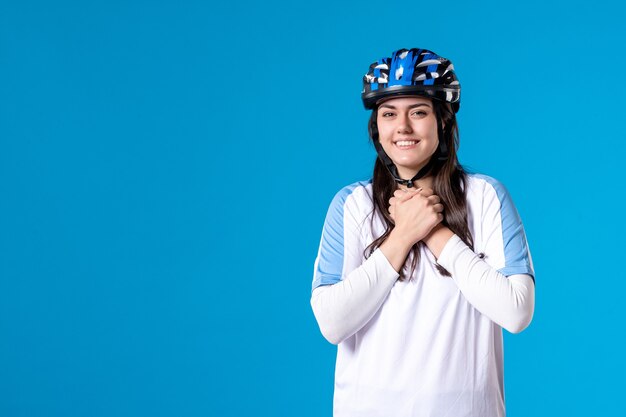 Vue de face jeune femme en vêtements de sport avec casque sur mur bleu