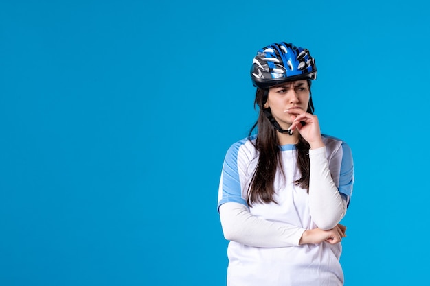 Vue de face jeune femme en vêtements de sport avec casque sur mur bleu