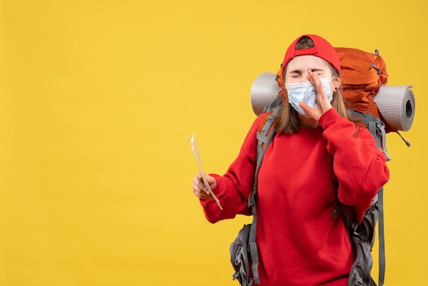 Vue de face jeune femme voyageur avec sac à dos et masque tenant la carte appelant quelqu'un