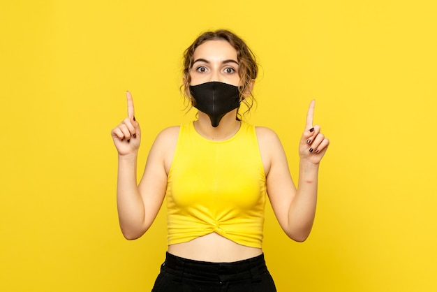 Photo gratuite vue de face de la jeune fille au masque noir sur mur jaune