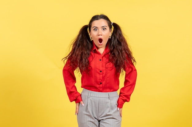 Vue de face jeune fille en blouse rouge avec visage choqué sur fond jaune couleur innocence enfant fille jeunesse kid