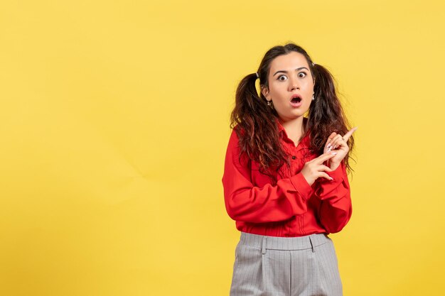 Vue de face jeune fille en blouse rouge avec visage choqué sur fond jaune innocence enfant fille jeunesse couleur enfant