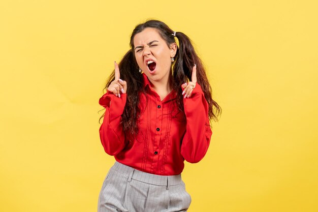 Vue de face jeune fille en chemisier rouge avec visage hurlant sur fond jaune femme enfant fille jeunesse sentiment d'émotion