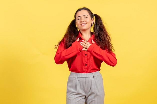 Vue de face jeune fille en chemisier rouge avec visage en relief sur fond jaune couleur innocence enfant jeunesse kid girl