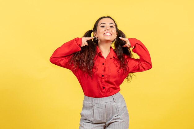 Vue de face jeune fille en chemisier rouge avec visage souriant sur fond jaune couleur innocence enfant jeunesse kid girl