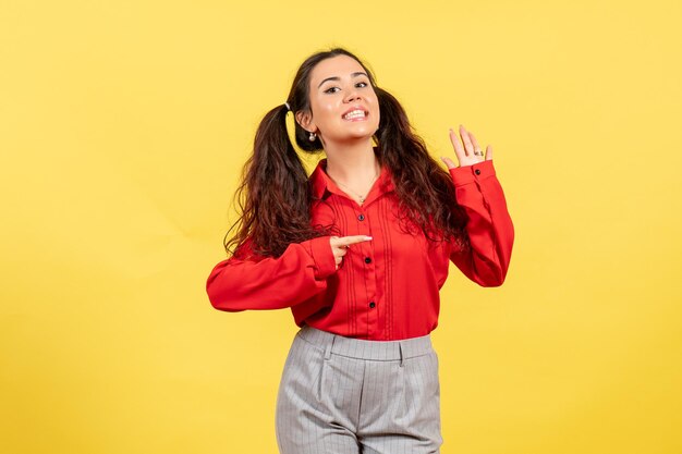 Vue de face jeune fille en chemisier rouge avec visage souriant sur fond jaune couleurs innocence enfant jeunesse kid girl