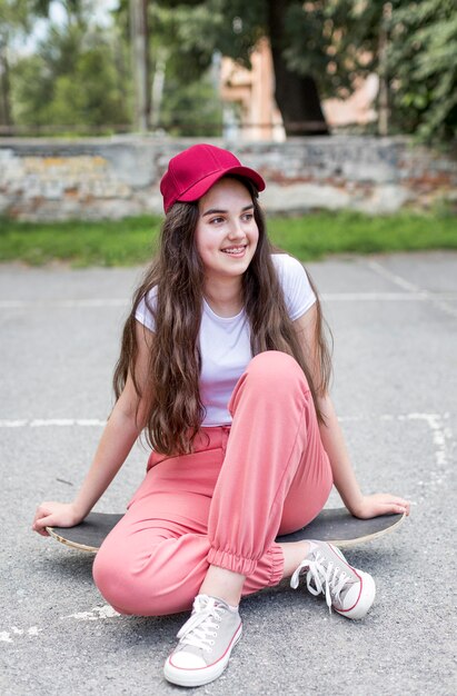 Vue de face jeune fille posant sur sa planche à roulettes