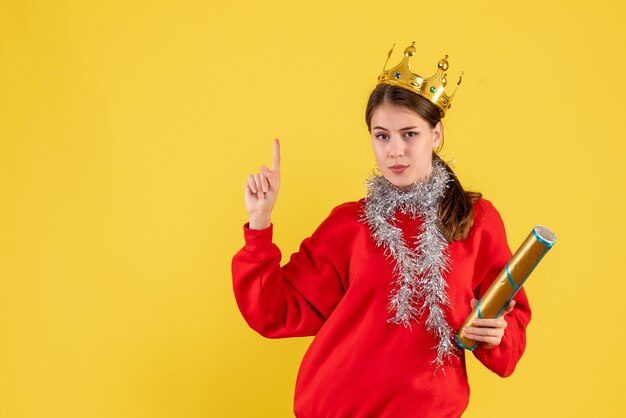 Vue de face jeune fille avec pull rouge tenant popper partie pointant avec le doigt vers le haut