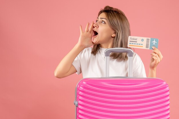 Vue de face jeune fille avec une valise rose tenant un ticket appelant quelqu'un