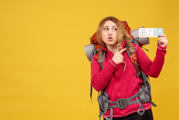 Vue de face de jeune fille voyageuse choquée dans un masque médical tenant et pointant un billet