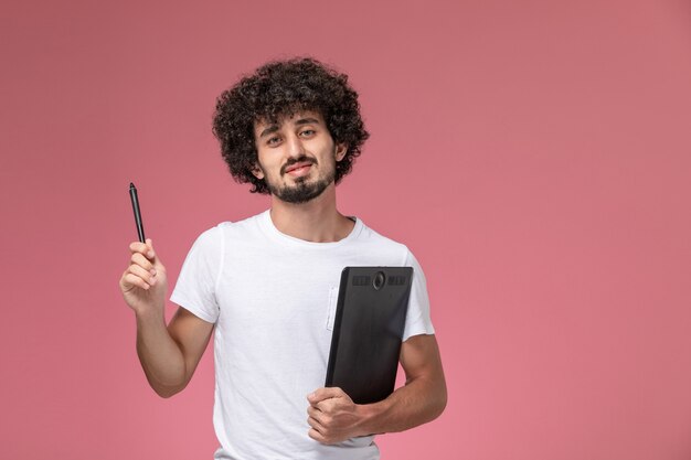 Vue de face jeune homme à l'aide de son stylo et tenant un cahier