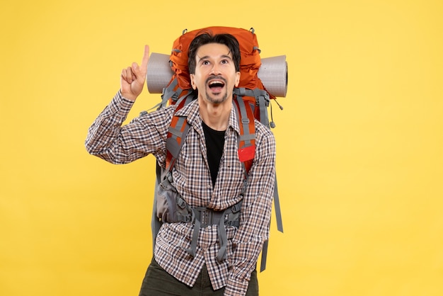 Vue de face jeune homme allant en randonnée avec sac à dos sur le campus de hauteur de couleur humaine de montagne touristique de fond jaune