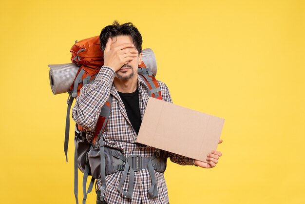 Vue de face jeune homme allant en randonnée avec sac à dos sur le fond jaune carte couleur société voyage campus air forêt nature