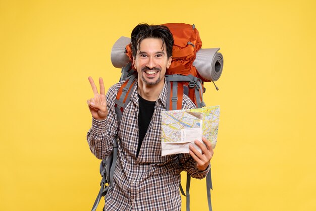 Vue de face jeune homme allant en randonnée avec sac à dos observant la carte sur fond jaune forêt entreprise voyage nature campus couleur air