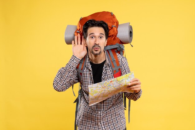 Vue de face jeune homme allant en randonnée avec sac à dos tenant une carte sur fond jaune voyage air nature société campus couleur de la forêt