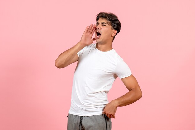 Vue de face jeune homme appelant en t-shirt blanc sur fond rose couleur modèle émotion mâle