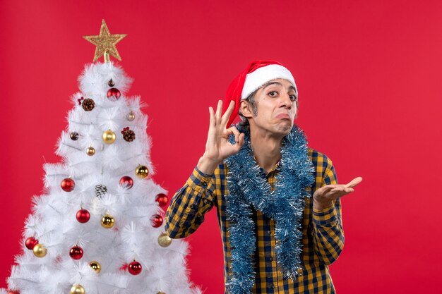 Vue de face jeune homme autour de l'atmosphère du nouvel an sur un mur rouge vacances de Noël de couleur