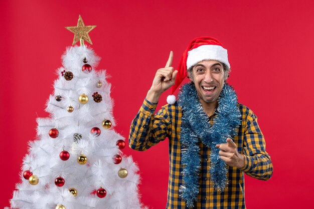 Vue de face jeune homme autour de l'atmosphère du nouvel an sur un mur rouge vacances de Noël humain