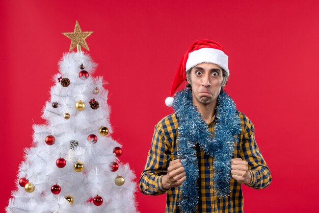 Vue de face jeune homme autour de l'atmosphère du nouvel an sur le plancher rouge émotion vacances Noël