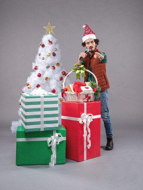 Vue de face jeune homme autour de cadeaux sur le gris