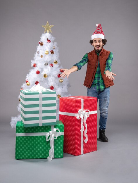 Vue de face jeune homme autour de cadeaux sur le gris