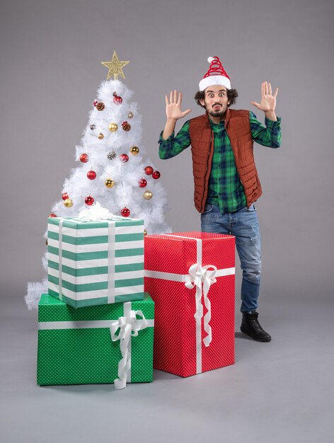 Vue de face jeune homme autour de cadeaux sur le gris