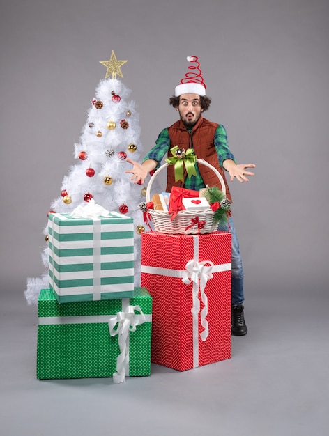 Vue de face jeune homme autour de cadeaux de vacances sur un bureau lumineux cadeau de Noël humain nouvel an